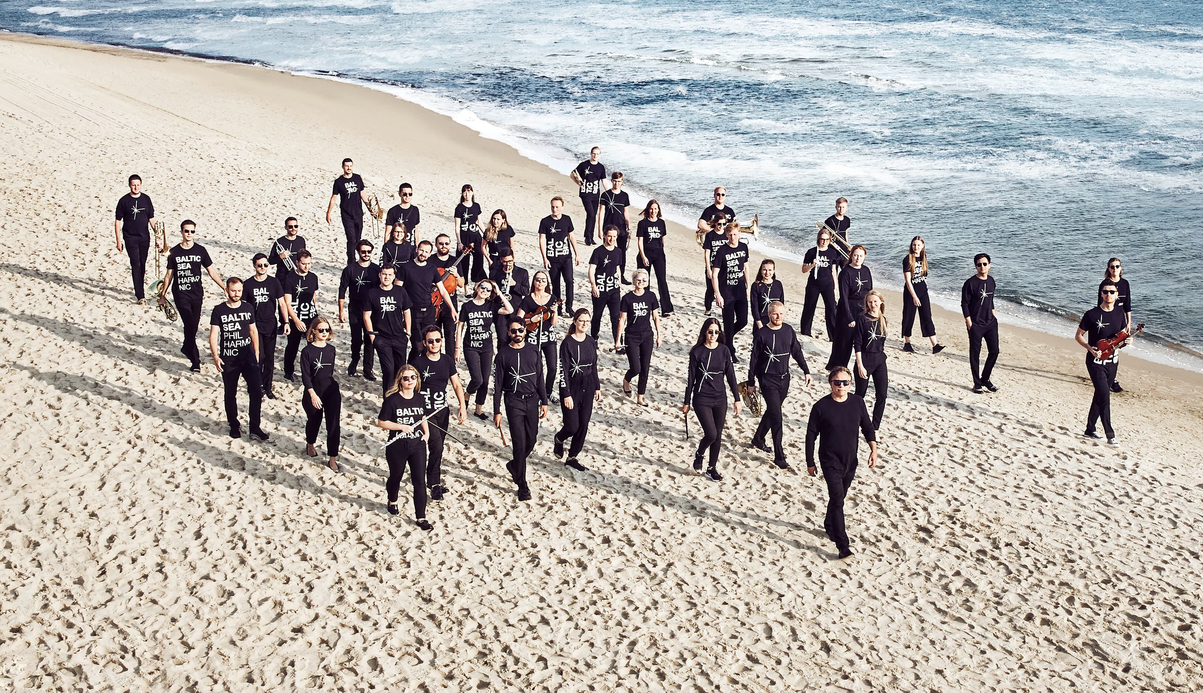 Gehende Musiker mit Instrumenten am Ostseestrand