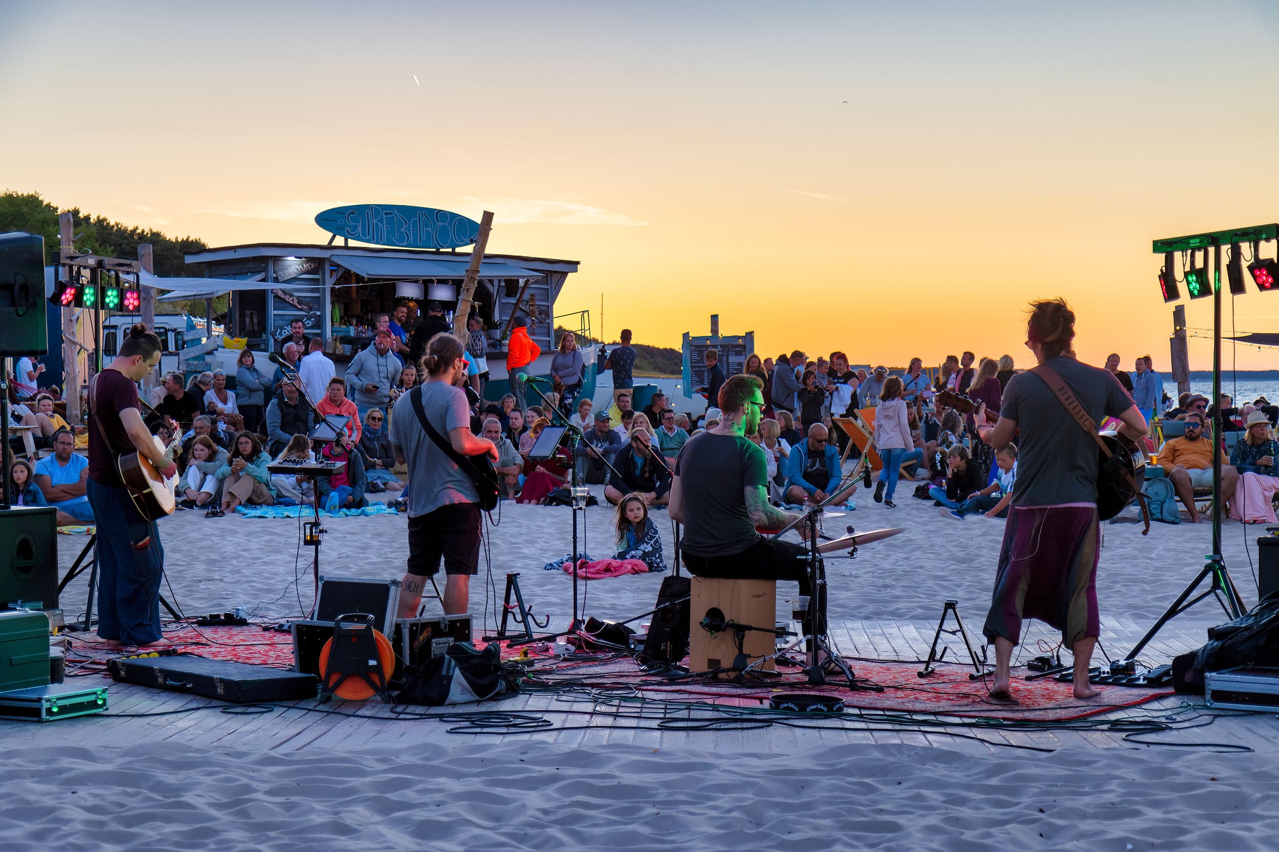 Das Bild zeigt ein Konzert am Strand von Zinnowitz auf der Insel Usedom. Es ist ein lauer Sommerabend mit Sonnenuntergangsstimmung.