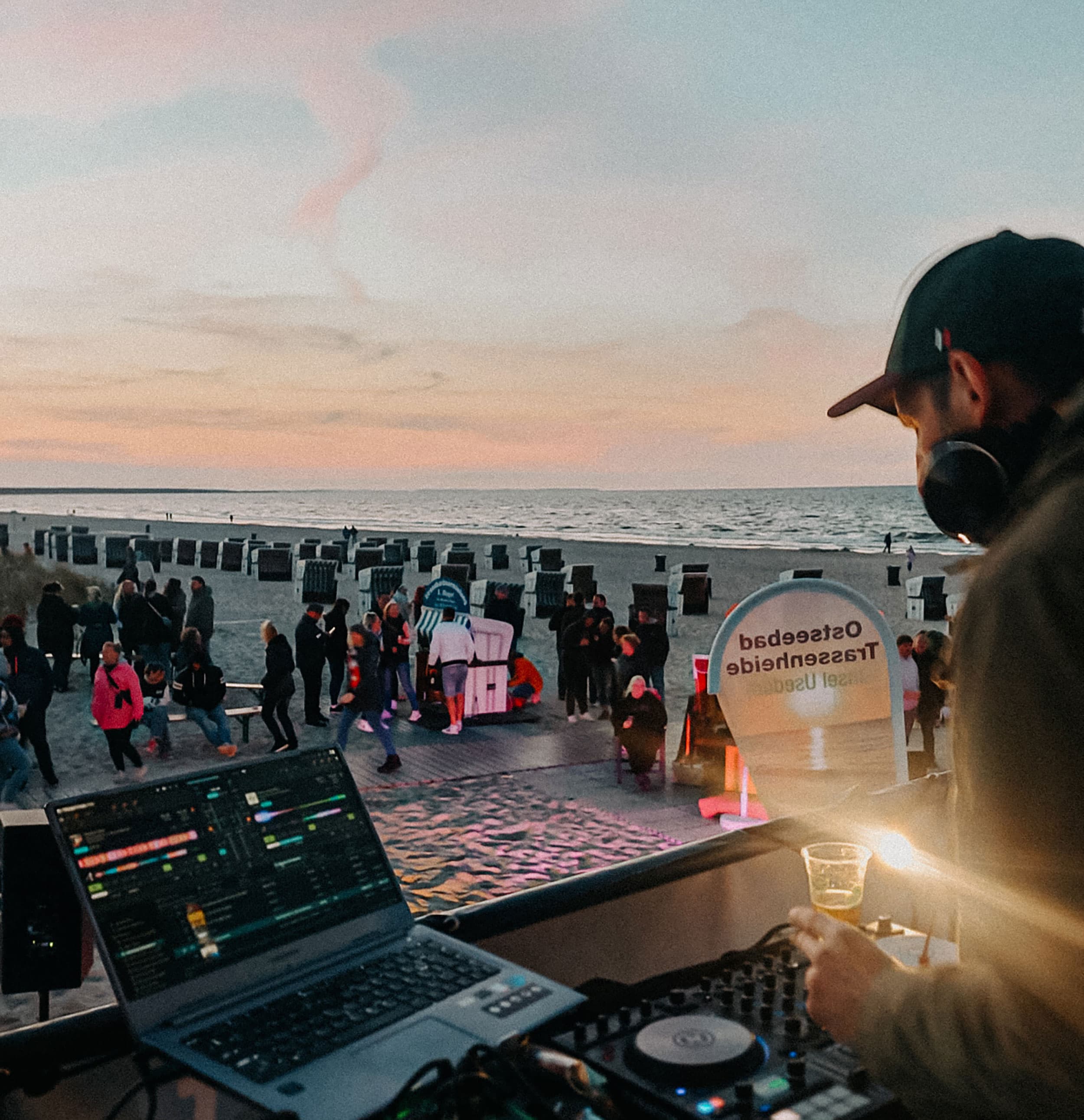 Das Bild zeigt einen DJ am Strand von Zinnowitz, der zum Sonnenuntergang Musik auflegt.