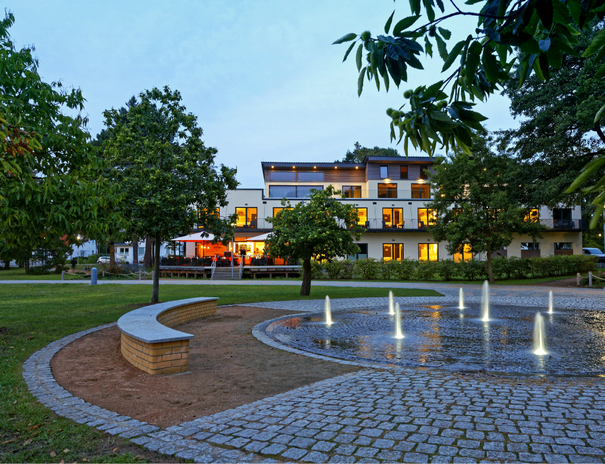 Frontansicht eines Hotels im Grünen, mit vorgelagertem Springbrunnen