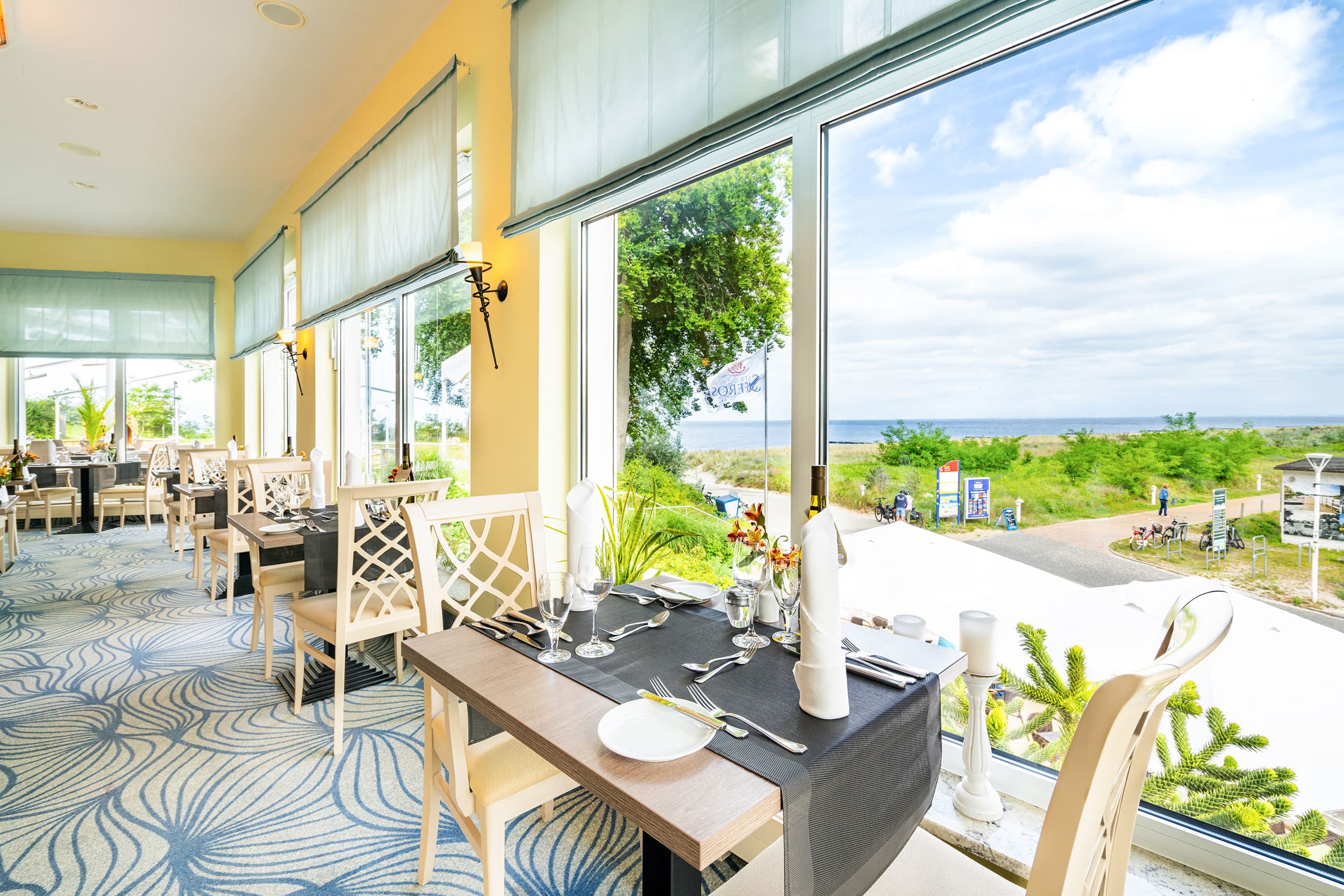 Das Bild zeigt das Restaurant im Strandhotel Seerose im Seebad Kölpinsee. Es zeigt den schönen Blick nach durch ein Panoramafenster nach draußen.